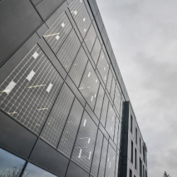 Das Bild zeigt die Fassade eines modernen Gebäudes mit integrierten Solarpaneelen.