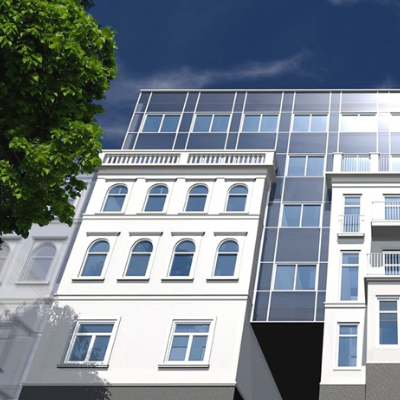 Das Bild zeigt eine moderne Gebäudefassade mit einem Mix aus klassischer Altbauarchitektur und gläsernem Neubau unter blauem Himmel.
