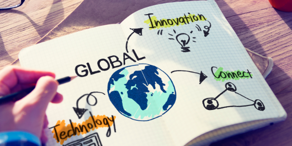 Das Bild zeigt ein aufgeschlagenes Notizbuch mit einer gezeichneten Weltkugel und Begriffen wie Innovation, Technologie und Vernetzung sowie eine Hand, die darauf schreibt.