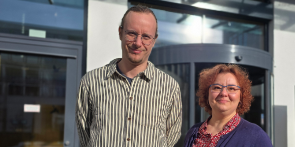 Das Bild zeigt zwei sich reichende Hände vor einer Stadtansicht, in die Silhouetten von Menschen in Geschäftsbesprechungen eingeblendet sind.